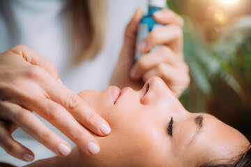 Obraz na płótnie Canvas Cosmetician Applying Hyaluronic Acid Serum on Woman’s Face