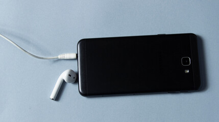 Fototapeta premium Mobile phone and wireless earpiece on white background