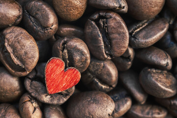 roasted coffee beans with toy little wooden red heart lying on the beans