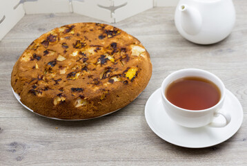 Sponge cake with  apples in a cast-iron pan, homemade, tea and kettle on the table