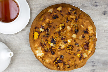Sponge cake with  apples in a cast-iron pan, homemade, tea and kettle on the table