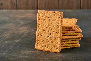 Cracker with flax seeds and oat bran rectangular shape for healthy, dietary and balanced diet on dark wooden background. Snack for proper nutrition.