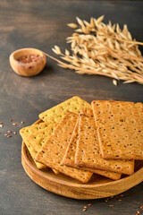 Cracker with flax seeds and oat bran rectangular shape for healthy, dietary and balanced diet on dark wooden background. Snack for proper nutrition.