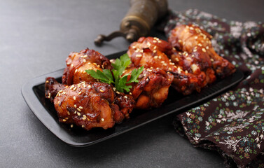 Plate of chicken wings in soy sauce with honey and sesame. Traditional asian recipe. Dark background.