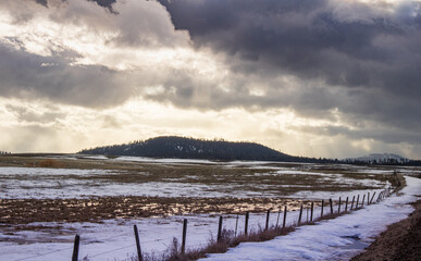 Clouds over the mountains and wet snowy field