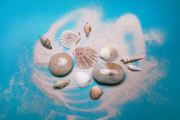 Obraz na płótnie Canvas Sea shells and beach sand on the blue background. Top view, elegant flat lay.