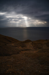 Sun rays make their way through dramatic clouds. Weather turns bad in the evening. Beautiful seascape. Vertical image