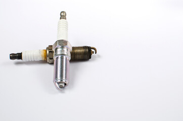 New and old car spark plug lie on a white background..Result before and after..Car parts..Car maintenance.