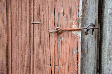 Old wooden door, brown, closed on a metal hook. Close-up. Vintage