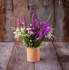 A bouquet of wild flowers. Summer wild flower. Wooden background and table. Place for text. Small Phalacrol and Veronica spicata. Copy space