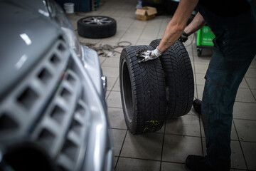 Car mechanic changind tires of a car in a repair shop/car garage (shallow DOF/color toned image)
