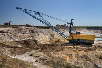 A dragline walking excavator works in a clay quarry.