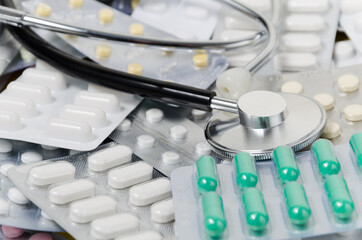 A pile of medical pills and capsules and a stethoscope