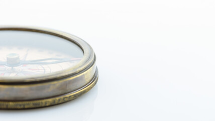 Closeup view of a brass vintage compass on white background. A compass is a magnetometer used for navigation and orientation that shows direction  relative to geographic cardinal directions