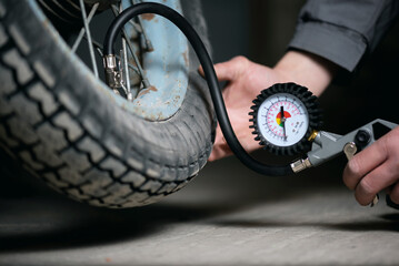 A worker is inflating a motorbike wheel by the car tyre inflating gun close up.