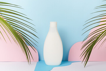 White clear tube for skincare bottle on blue background with palm tropical leaves . Skincare spray tube for helthcare concept. shampoo or gel