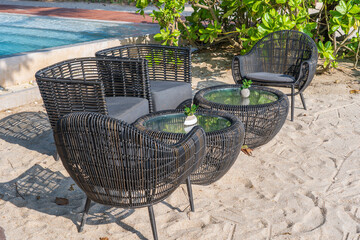 Wicker chairs and table in empty beach cafe next to sea. Close up. Thailand