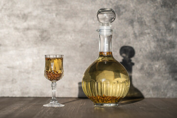 Homemade birch buds tincture in a glass bottle and a wine crystal glass on a wooden table background