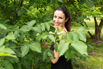 A beautiful woman standing between trees in a garden.