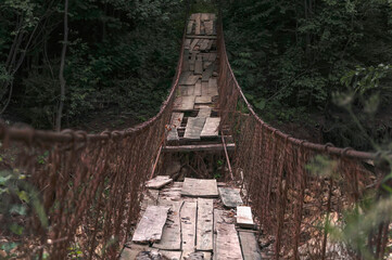 Destroyed suspension bridge over a mountain river (concept: dangerous path)