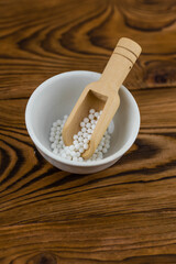 Homeopathy alternative medicine eco concept - classical homeopathy pills. Homeopathic globules on wooden background. 