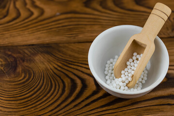 Homeopathy alternative medicine eco concept - classical homeopathy pills. Homeopathic globules on wooden background. 