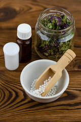 Homeopathy alternative medicine eco concept - classical homeopathy pills. Homeopathic globules and healing herbs. Wooden background. 