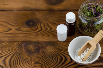 Obraz na płótnie Canvas Homeopathy alternative medicine eco concept - classical homeopathy pills. Homeopathic globules and healing herbs. Wooden background. 