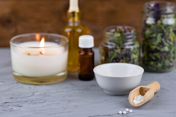 Homeopathy alternative medicine eco concept - classical homeopathy pills. Homeopathic globules, natural organic aroma oil essence and healing herbs. Wooden background. 