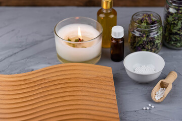 Homeopathy alternative medicine eco concept - classical homeopathy pills. Homeopathic globules, natural organic aroma oil essence and healing herbs. Wooden background. 