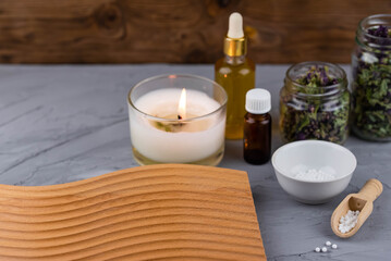 Homeopathy alternative medicine eco concept - classical homeopathy pills. Homeopathic globules, natural organic aroma oil essence and healing herbs. Wooden background. 