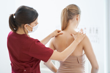 Physiotherapist in mask helping female patient