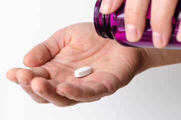 A large white pill lies in a man's hand. Health. Medicine