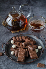aerated milk chocolate on the background of a cup of tea and a teapot