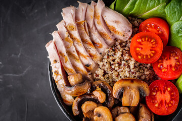 bowl of healthy quinoa with grilled chicken and vegetables on a dark rustic background