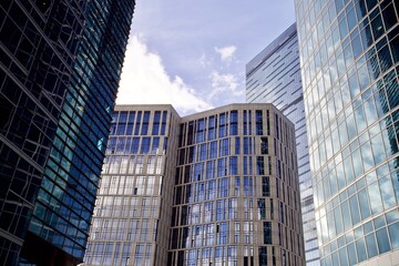 Office and residential skyscrapers against bright sun and clear blue sky close up. Reflections and...
