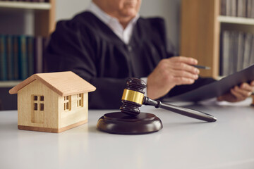 Close-up of judge's gavel, sound block, and small wooden toy house on courtroom table in court....