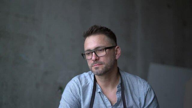 'I have got an idea' or 'Eureka' concept. Bearded workman or painter in glasses and apron looking off from camera and made a gesture to have an idea. 4K footage