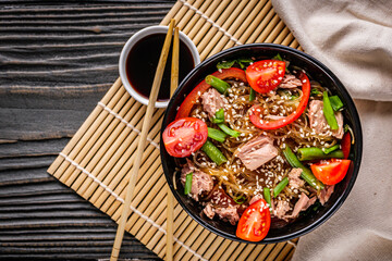 delicious glass noodles with tuna and vegetables on a dark wooden rustic background