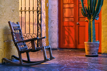 A house facade in Arequipa, Peru, with a rocking chair, a door  and a cactus