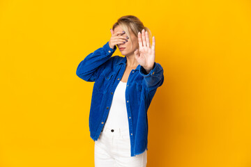 Young Russian woman isolated on yellow background making stop gesture and covering face