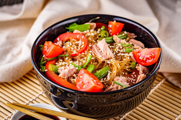 delicious glass noodles with tuna and vegetables on a dark wooden rustic background