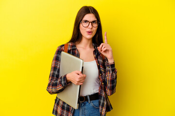 Young caucasian student woman holding a laptop isolated on pink background having some great idea,...