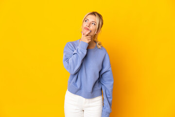 Young Russian woman isolated on yellow background having doubts