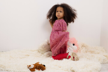 Portrait images of a 3-year-old African girl standing on a light blanket on the floor with a face depicting anger and resentment, a concept for Children with emotional expressions.