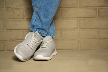 Woman wearing casual clothing and white sneakers leaning wall in city.