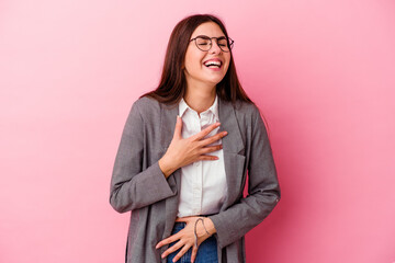 Young caucasian business woman isolated on pink background laughs happily and has fun keeping hands on stomach.