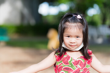 Cute girl playing in hot sun. Child sweats on forehead. Children puts mask under chin from...
