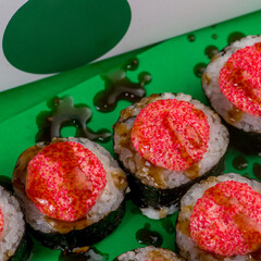 Sushi with seafood in nori on a green background. Close-up