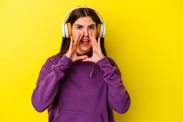 Young caucasian woman listening to music with headphones isolated on pink background shouting excited to front.